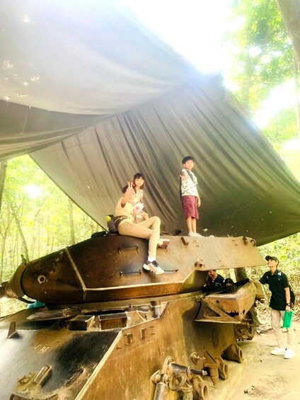 A large, rusted military tank in a forested area with people around it. 5