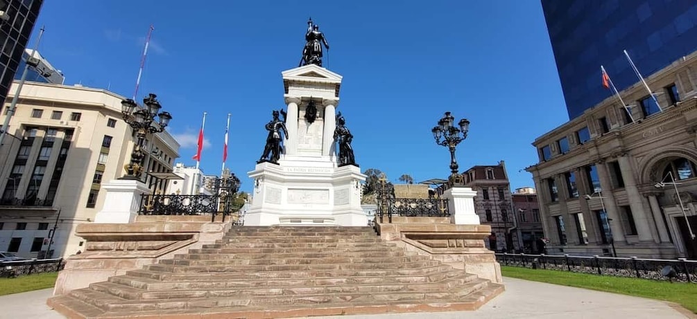 Ett vitt monument med trappsteg som leder upp till det, omgivet av byggnader och flaggor. 2