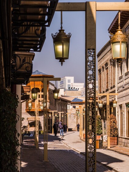 A street with traditional architecture, hanging lanterns, and people walking. 5