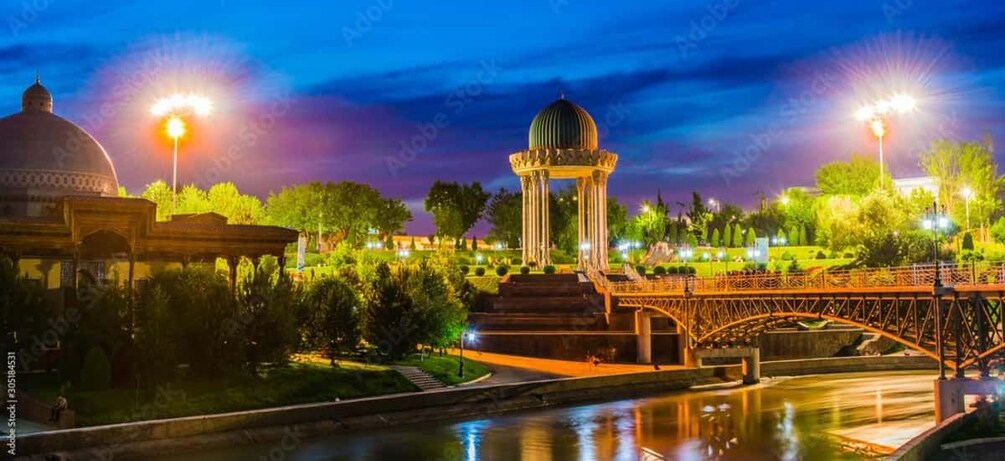 A night scene with a bridge, a gazebo, and a river reflecting lights. 2