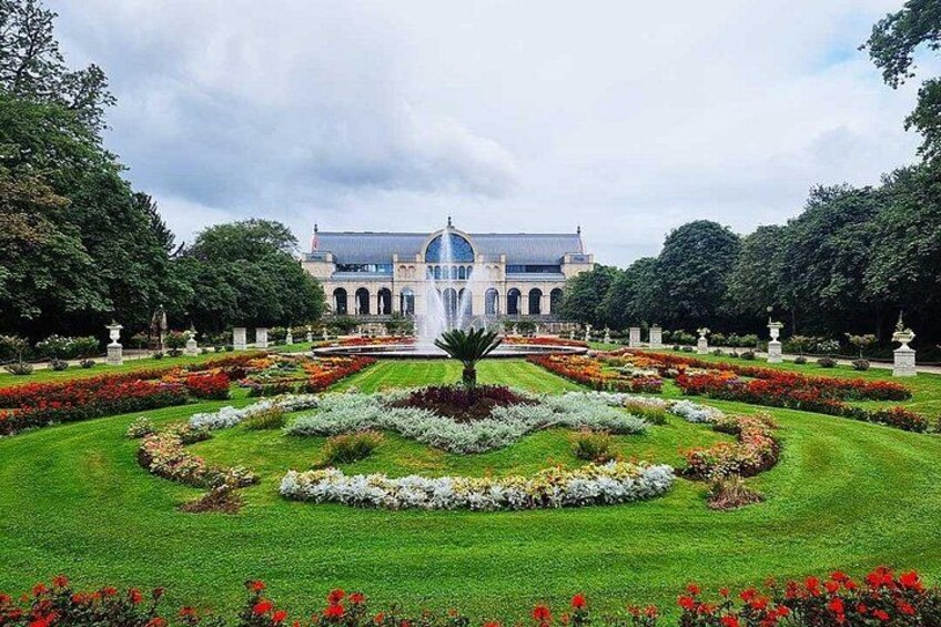 A grand building with a dome, surrounded by a well-manicured garden with a central fountain. 1