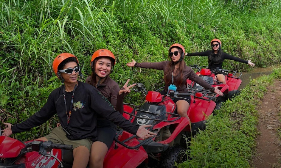 Four people on red ATVs in a grassy area. 3