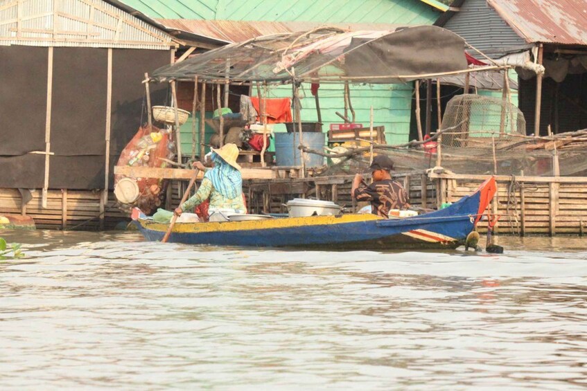 A traditional boat with people on it, docked near a wooden structure with a green roof. 5