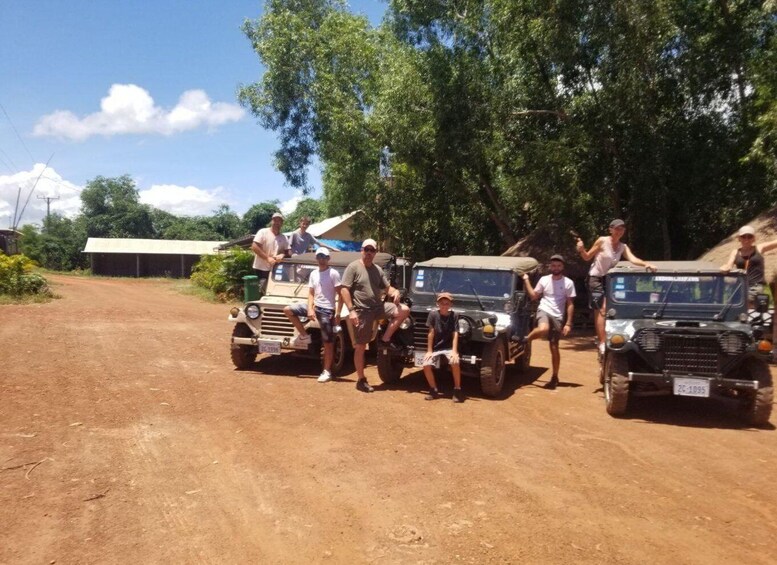 A group of people posing with two off-road vehicles on a dirt road. 1