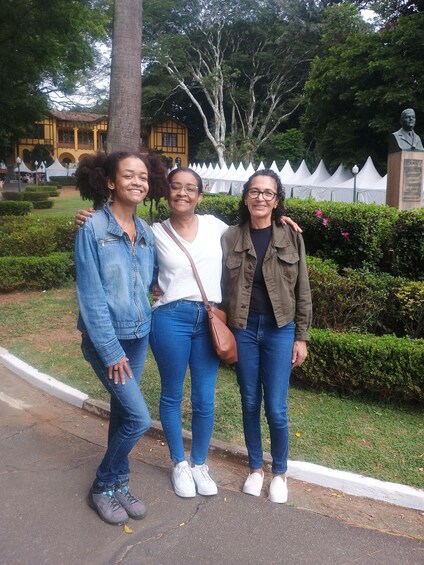 Three people standing on a paved path with a park and a building in the background. 5