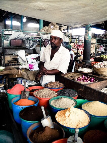 A market stall with various spices and grains displayed in colorful containers. 1