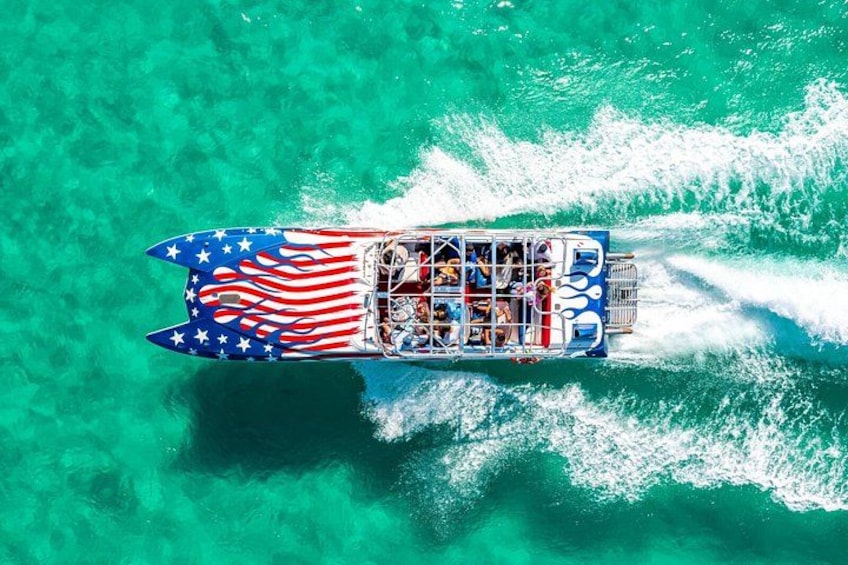 A boat with an American flag design, moving through clear turquoise water. 1