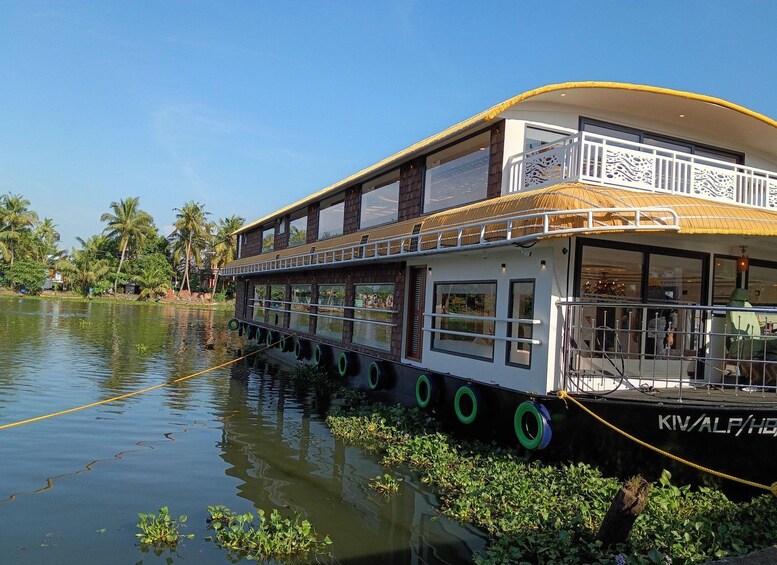 A houseboat docked on a calm river with lush greenery and palm trees in the background. 4