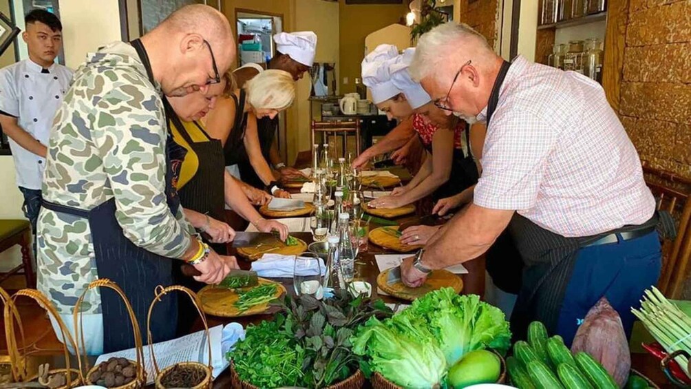 Chefs preparing food at a table with various vegetables and ingredients. 4
