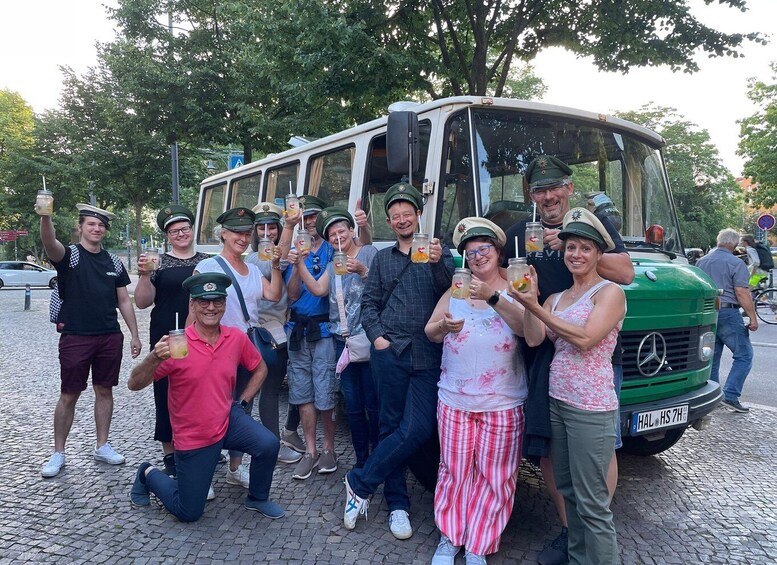 A group of people posing in front of a green vehicle with a license plate reading "HAL HS 7H". 1