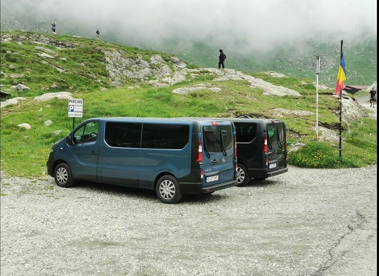 A blue van parked on a gravel road with a sign indicating parking with payment. 2