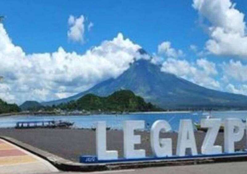 A mountain with a sign reading 'LEGAZP' in front of a body of water. 2
