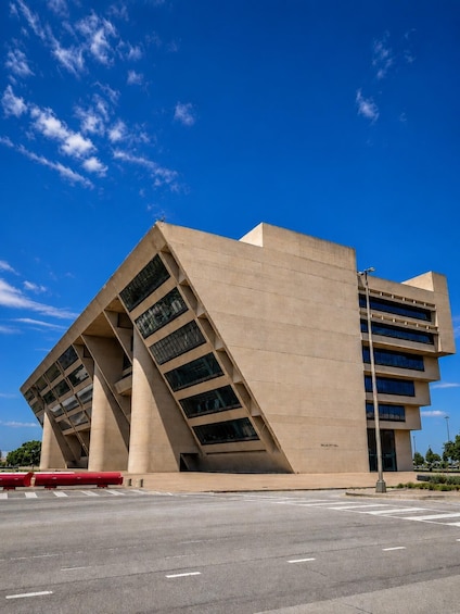 A modern building with a unique angular design, large windows, and a clear blue sky in the background. 2
