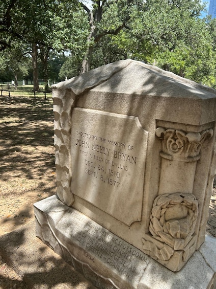A memorial stone with inscriptions, surrounded by trees. 3