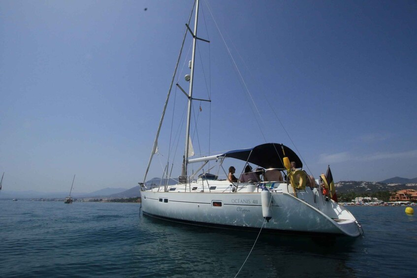 A sailboat named 'Oceanis 411' on calm waters with a clear sky and distant mountains. 1