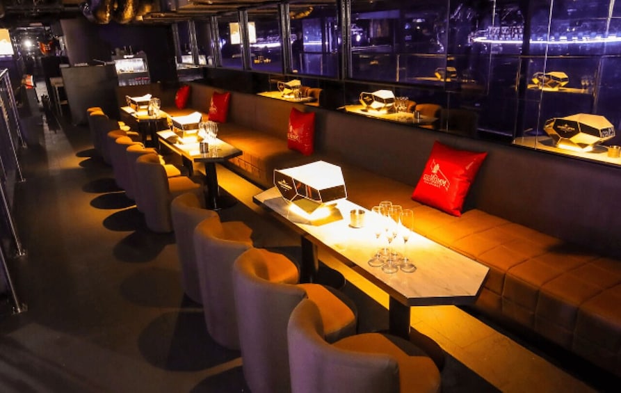 A modern bar with tables, cushioned seating, and red pillows. 3