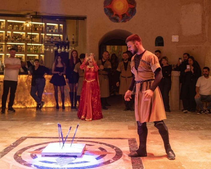 A person in medieval attire performing a ritual with candles in a room with a bar and people watching. 3