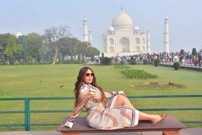 A person sitting on a bench with the Taj Mahal in the background. 4