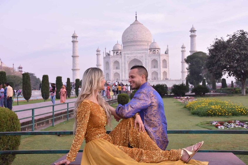 A couple sitting in front of the Taj Mahal with the mausoleum in the background. 2