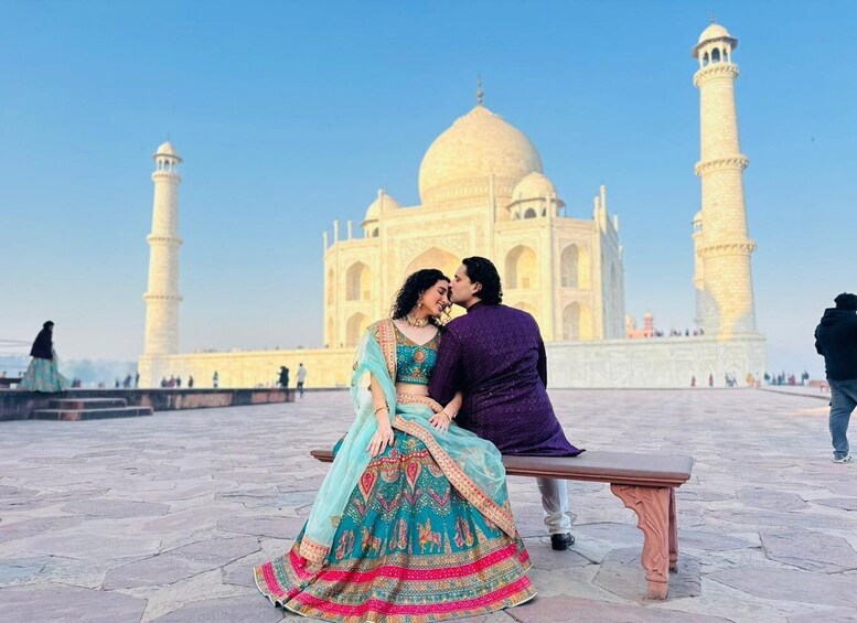 A couple sitting on a bench with the Taj Mahal in the background. 1
