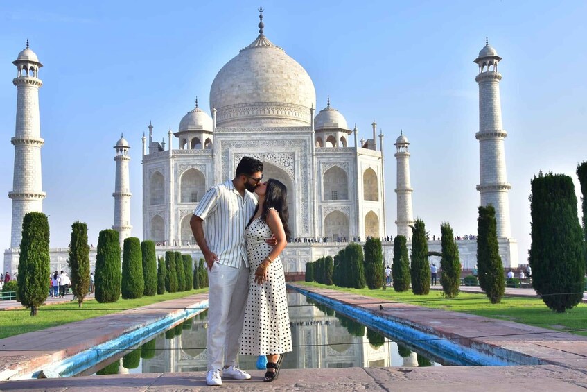 A couple standing in front of the Taj Mahal with its reflection in the water. 3