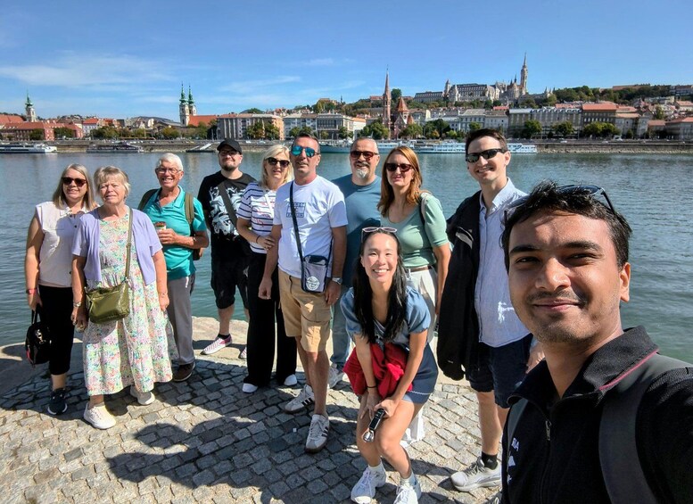 A group of people standing on a cobblestone waterfront with a cityscape in the background. 3