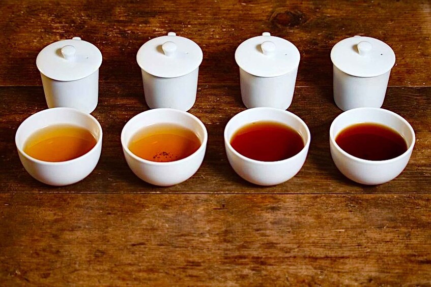 Six white ceramic cups and lids on a wooden surface. 1
