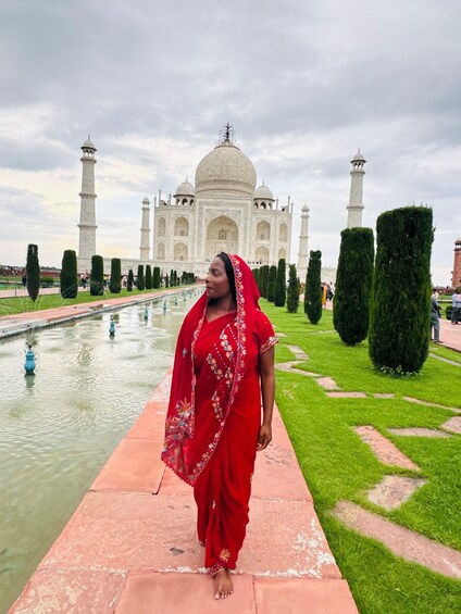 A woman in a red dress walking on a pathway with the Taj Mahal in the background. 5