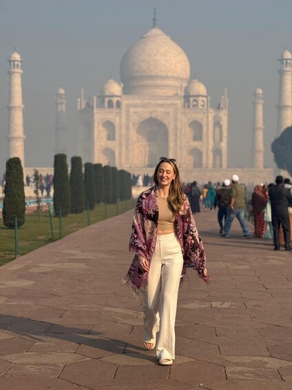A person walking on a paved pathway with the Taj Mahal in the background. 2