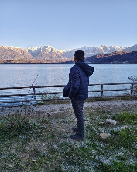 A person fishing by a lake with mountains in the background. 5