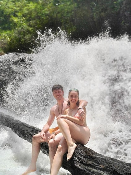 Two people sitting on a log in a waterfall. 5