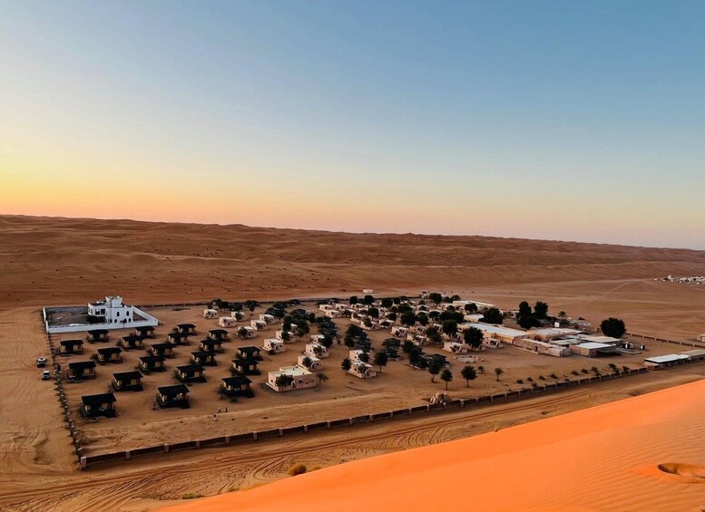 Paisaje desértico con un edificio blanco grande y numerosas estructuras pequeñas, probablemente un resort o campamento. 2
