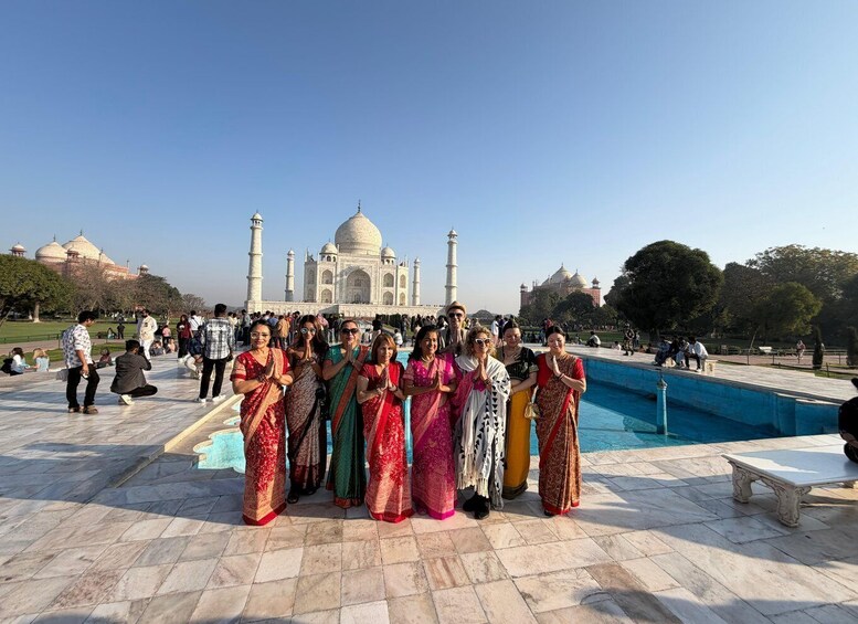 Ryhmä ihmisiä perinteisissä asuissa poseeraa Taj Mahalin edessä. 1