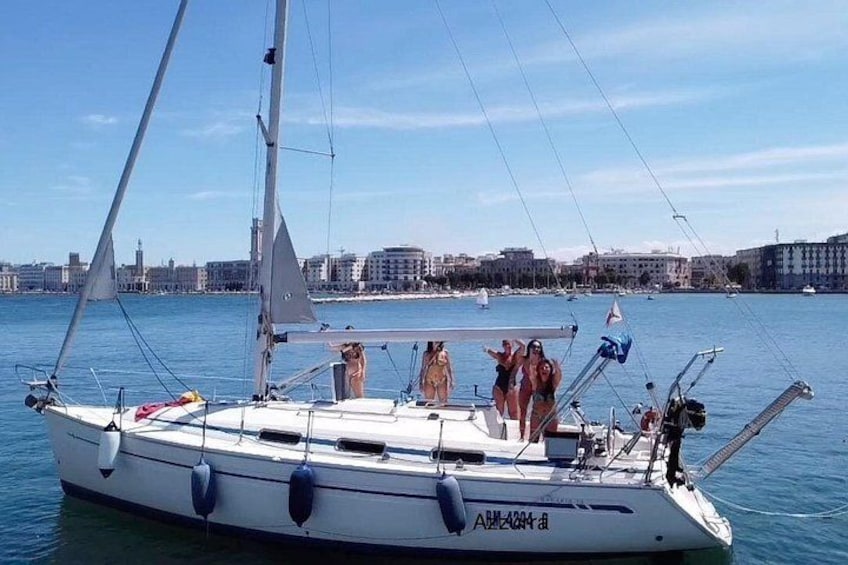Un velero con gente a bordo, un paisaje urbano al fondo y aguas tranquilas. 2