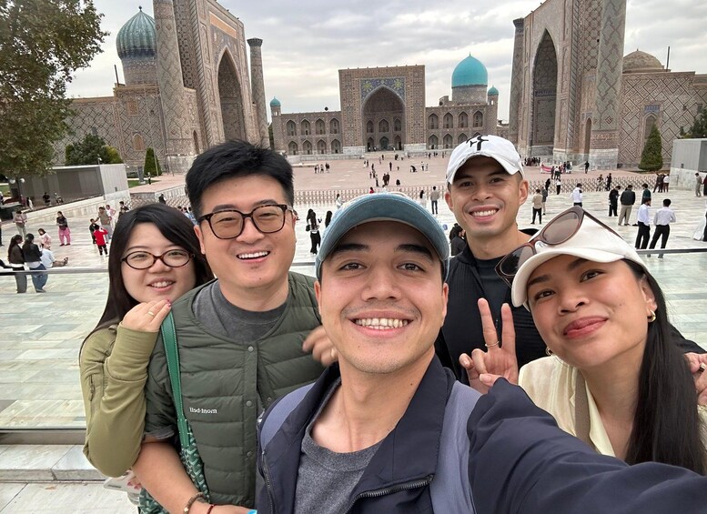 A group of people taking a selfie in front of a historic building with intricate architecture. 5