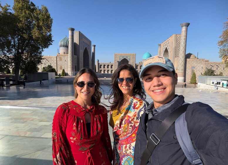 A group of people taking a selfie in front of a historic building with domes and arches. 2