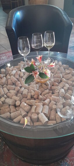 A table with a glass centerpiece surrounded by wine glasses and corks. 3