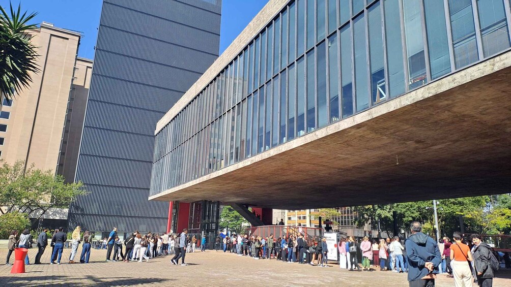 A modern building with a sloped roof and a crowd of people gathered in front. 2
