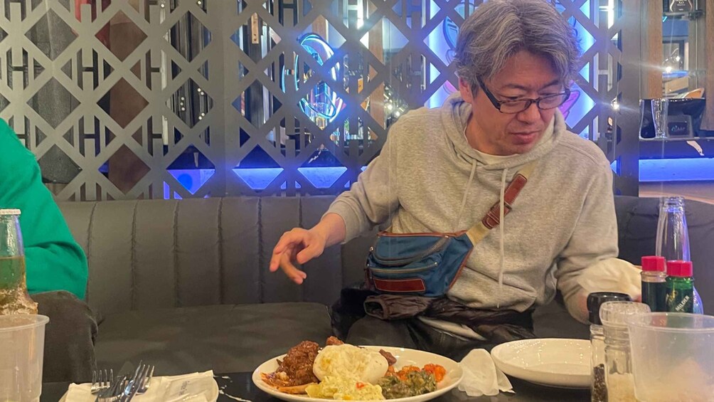A person sitting at a table with a plate of food, a water bottle, and a glass. 4
