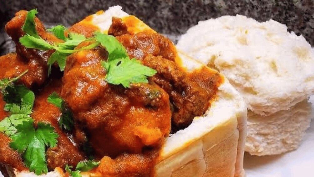A dish of curry with bread and a garnish of cilantro. 2