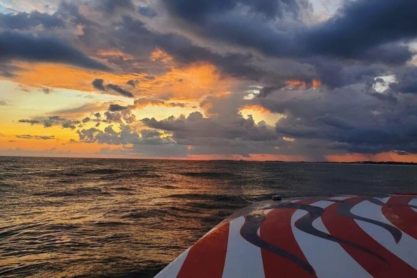 Tramonto sull'oceano con una vela a righe in primo piano. 1