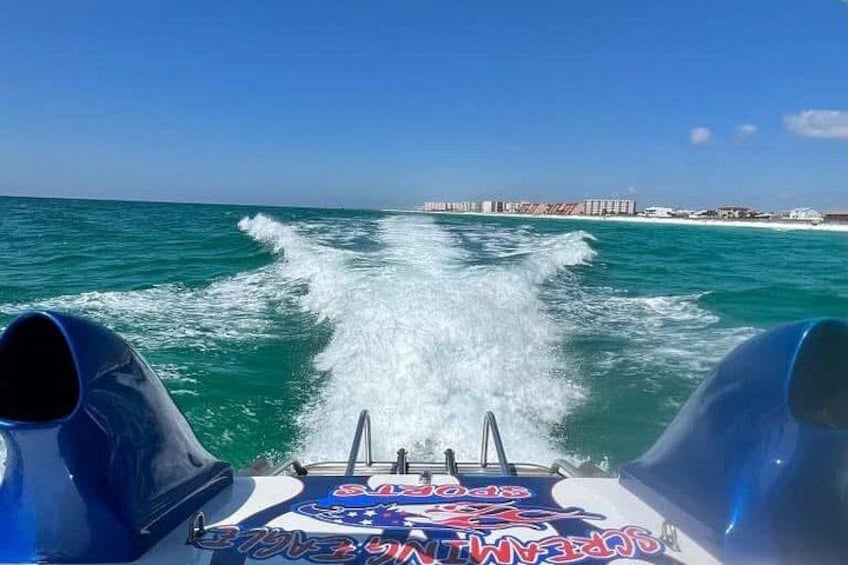 A jet ski speeding across turquoise water with waves trailing behind. 2