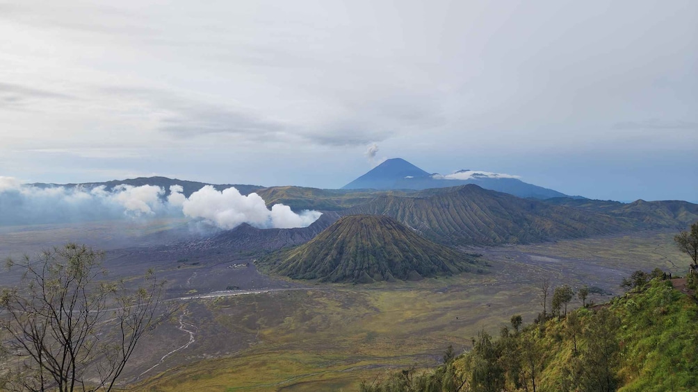 A volcanic landscape with a prominent volcano, a river, and surrounding hills. 2