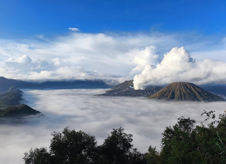 A mountain range with a prominent volcano, surrounded by clouds and forested areas. 5