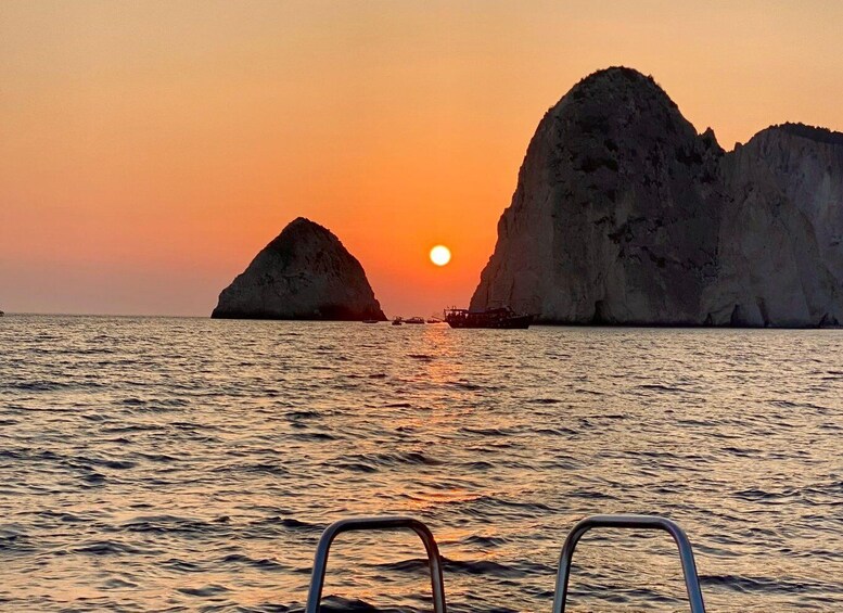 A sunset over the ocean with two large rock formations in the distance. 1