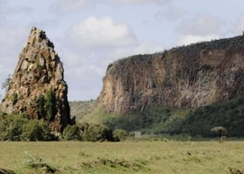 A rocky outcrop and a steep cliff in a grassy field. 1