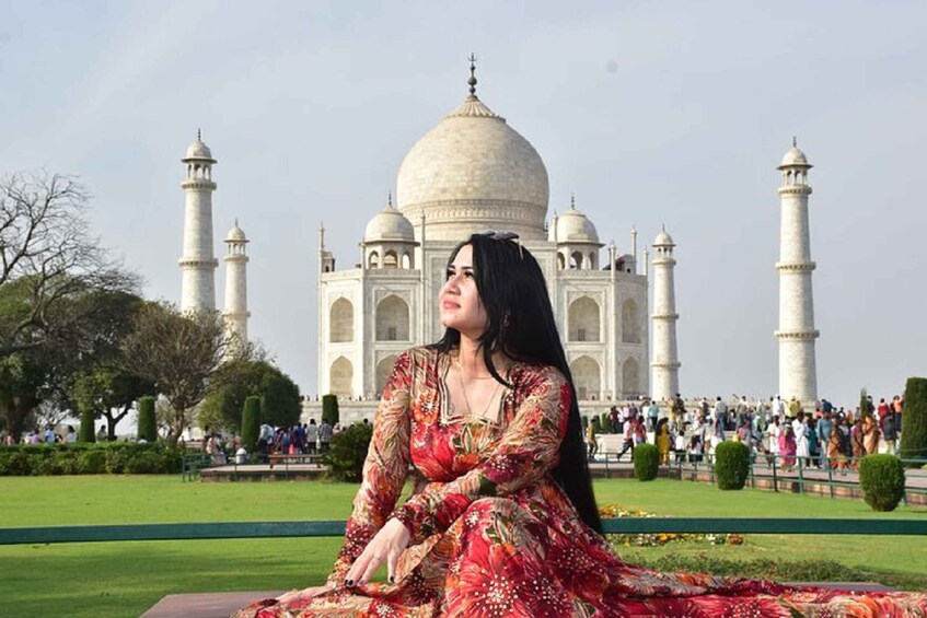 A woman in a floral dress sitting in front of the Taj Mahal. 5