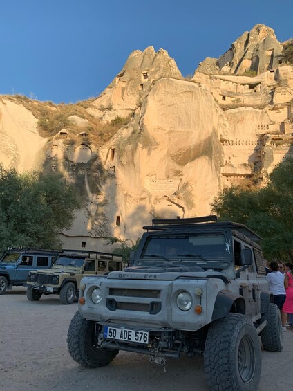 A desert landscape with rock formations and a parked off-road vehicle. 3