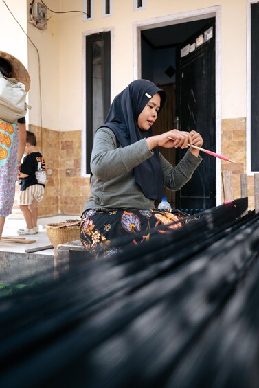 A person engaged in spinning thread with a spinning wheel. 2