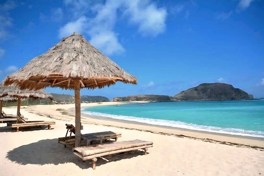 A beach with thatched umbrellas and wooden loungers. 1